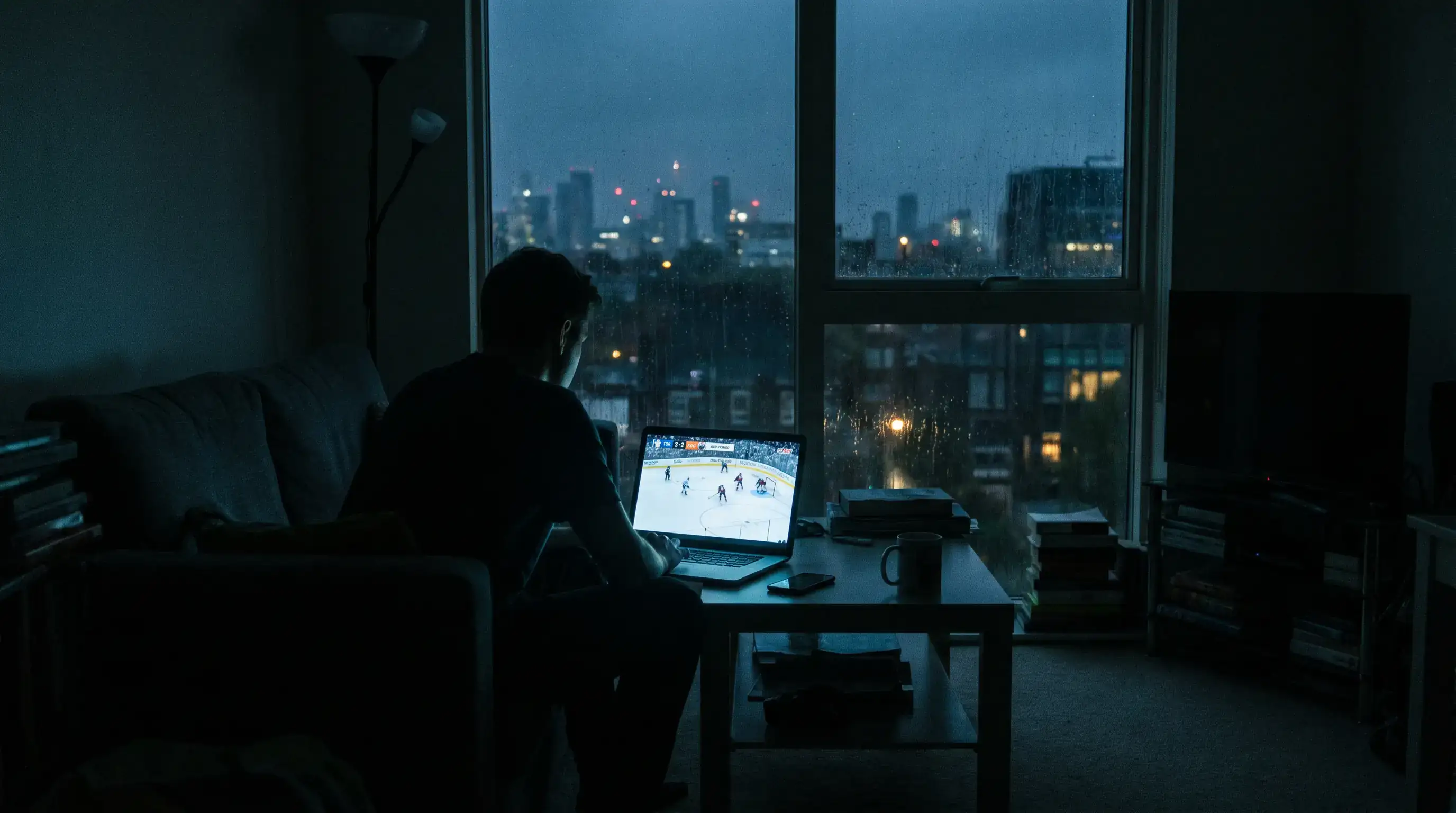 Dark living room at night with a glowing laptop screen showing a live NHL ice hockey game stream